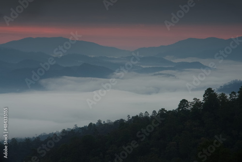 Fluffy sea of fog in a mountain valley with twilight sky in a morning