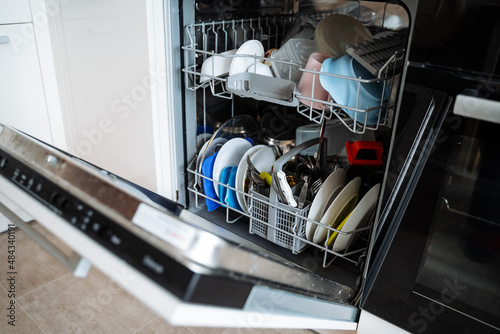Dishwasher. Equipment for washing plates. Loading the drawer with dishes. open door of kitchen appliances.