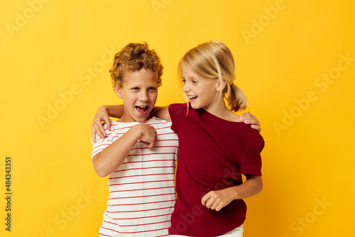 Boy and girl standing side by side posing childhood emotions on colored background