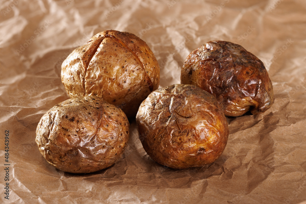 Whole baked potato tubers on brown kraft paper. Close-up. Whole baked potato tubers on brown kraft paper. Close-up.