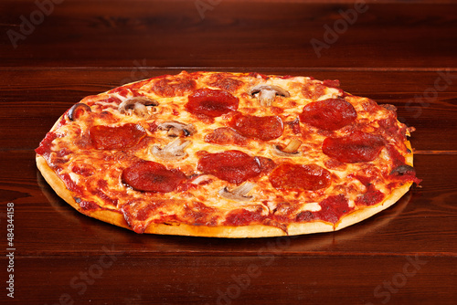 Tasty pepperoni pizza with mushrooms on wooden table. Angle view with copy space.