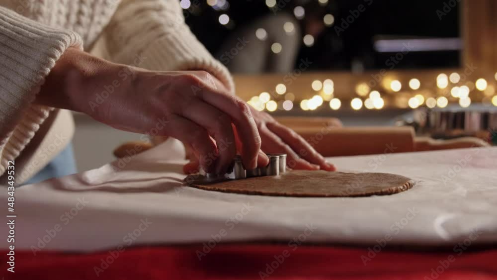 food, cooking and winter holidays concept - close up of woman with mold making gingerbread cookies from dough at home on christmas food, cooking and winter holidays concept - close up of woman with mold making gingerbread cookies from dough at home on christmas