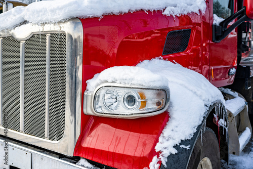 Fototapeta Naklejka Na Ścianę i Meble -  Shiny red big rig semi truck tractor standing for truck driver rest on the winter truck stop parking lot with snow and ice