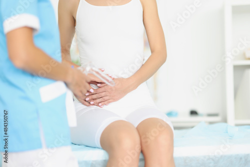 Gynecologist with medical instrument with mirror standing in front of woman with adnexitis photo