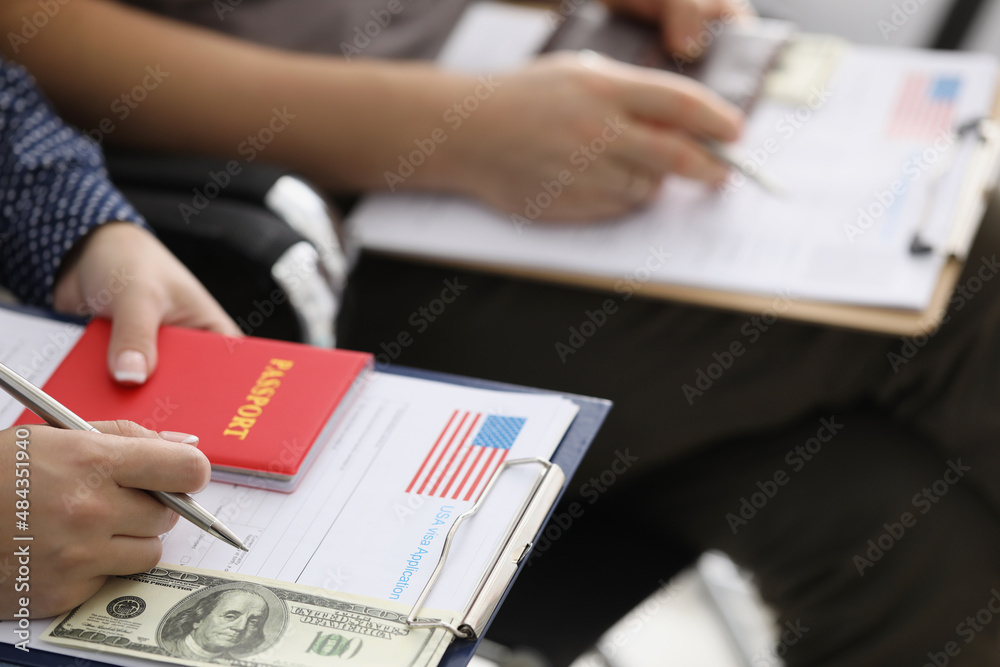 People sitting in line with documents for obtaining American visa and money closeup People sitting in line with documents for obtaining American visa and money closeup