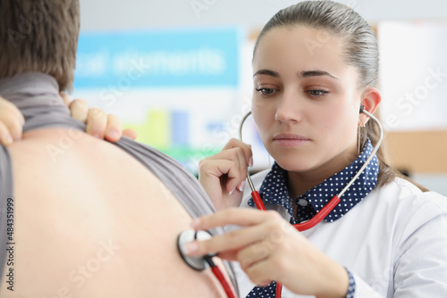 Woman pulmonologist listening to lungs of patient with stethoscope in clinic photo