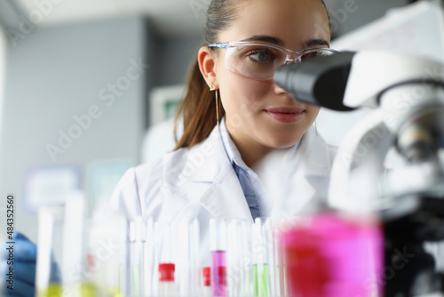 Woman scientist chemist looking through microscope in laboratory