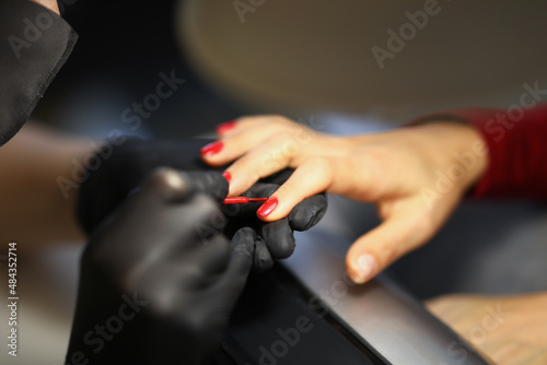 Manicurist painting woman nails with red varnish closeup