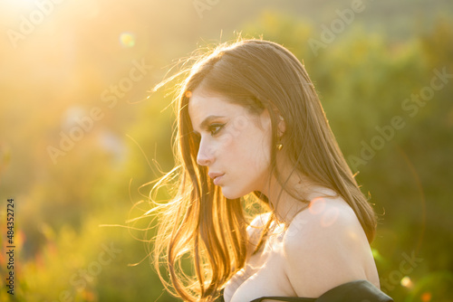 Portrait of beautiful young woman looking eways in summer park. Outdoor portrait of a cute girl. Happy cheerful female model, close up face. Young woman on sunny spring day. Soft sunny light. photo