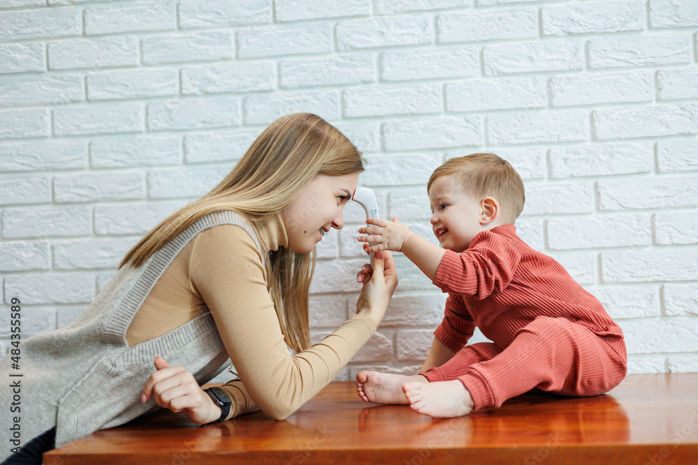 Mother and child measure body temperature with an electric thermometer. Non-contact thermometer Mother and child measure body temperature with an electric thermometer. Non-contact thermometer
