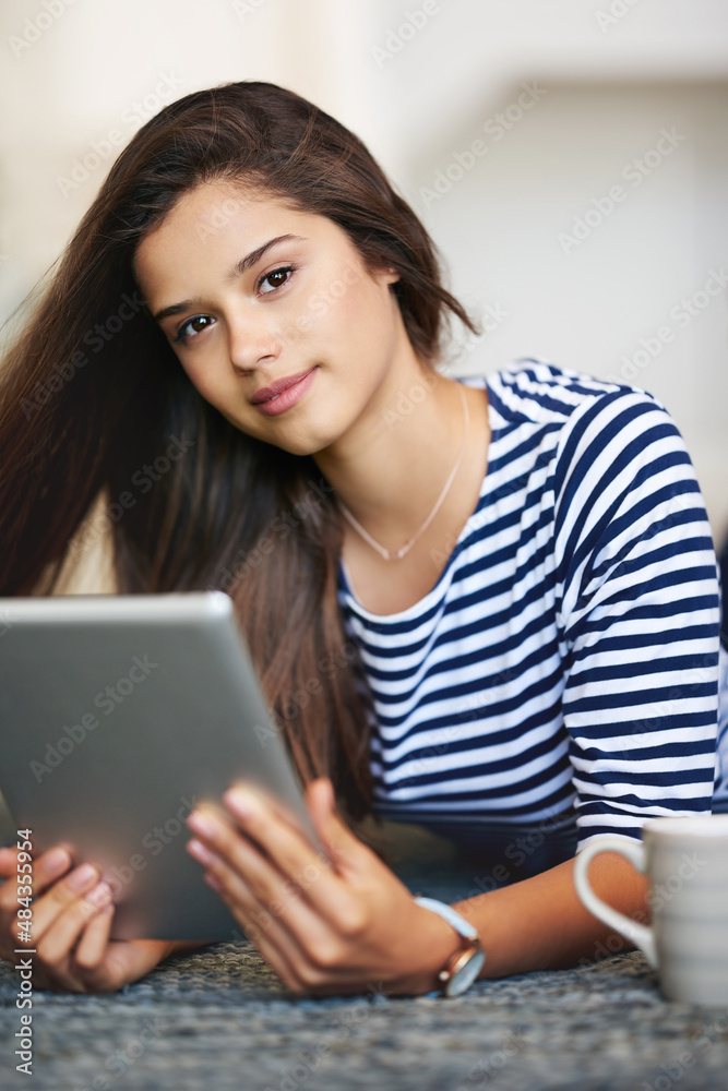 Staying portable and connected. Portrait of a smiling young woman lying on the floor at home using a digital tablet. Staying portable and connected. Portrait of a smiling young woman lying on the floor at home using a digital tablet.
