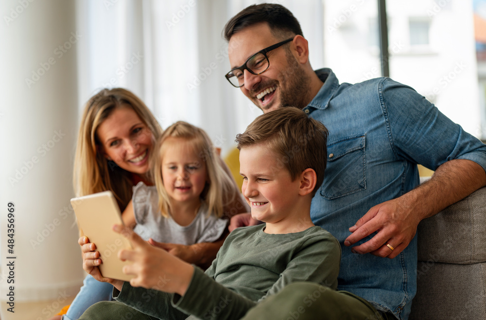 Happy young family having fun time at home. Parents with children using digital device. Happy young family having fun time at home. Parents with children using digital device.