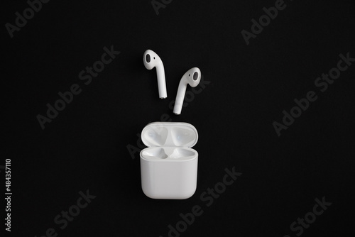 White wireless earbuds and plastic case on black background
