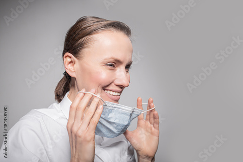 female doctor in medical mask on the face over grey wall background
