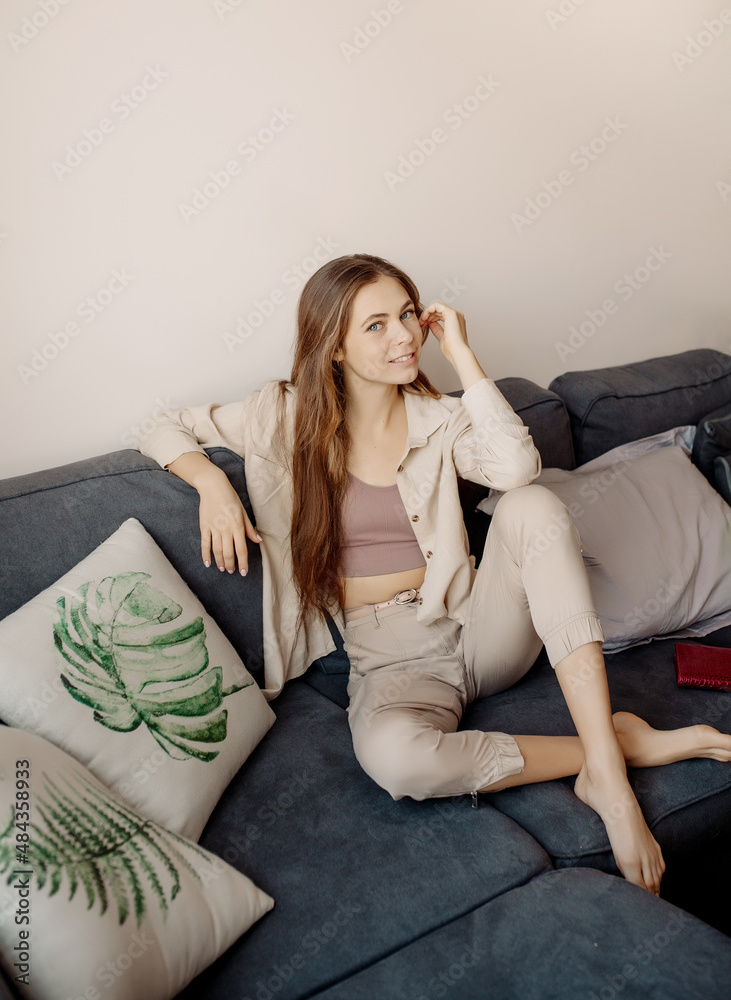 Fototapeta premium Young woman with book sitting at couch at home biophilic interior, many indoor trees