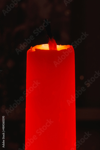 An extinguished orange candle against a dark background in the backlight.