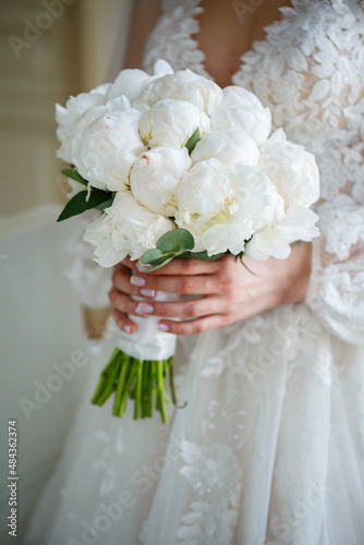 Hands of the bride close-up with a bouquet of fresh beautiful flowers. Attribute of the bride