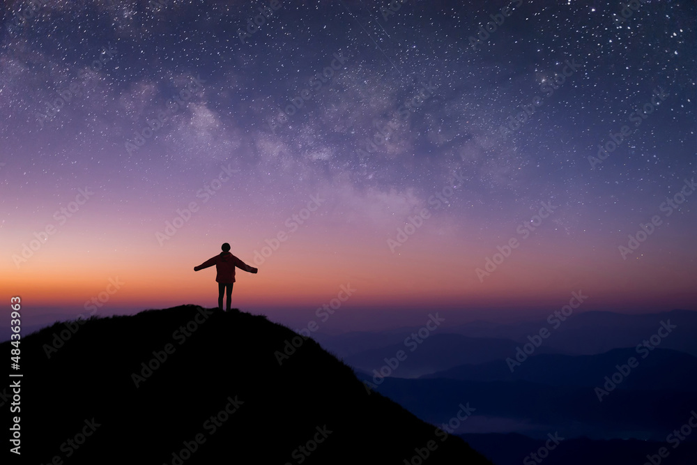 Silhouette of young traveler and backpacker open both arms and watched the star, milky way alone on top of the mountain. He enjoyed traveling and was successful when he reached the summit.