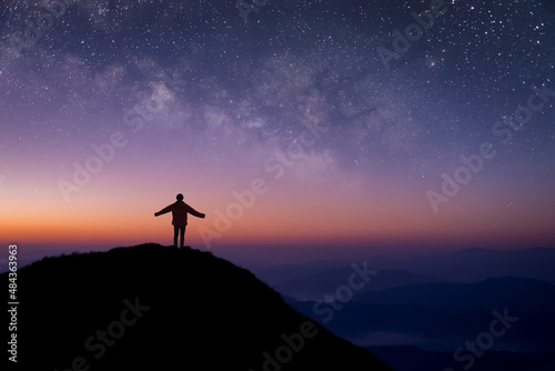 Silhouette of young traveler and backpacker open both arms and watched the star  milky way alone on top of the mountain. He enjoyed traveling and was successful when he reached the summit.