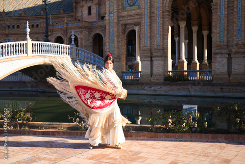 Flamenco dancer, woman, brunette and beautiful typical spanish dancer is dancing with a red manila shawl in a square in seville. Flamenco concept of cultural heritage of humanity.