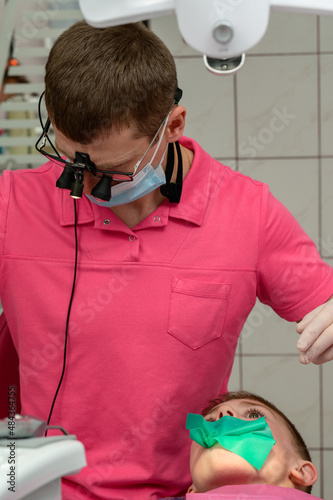 The dentist installs a rubber dam and a clamp for the treatment of a diseased tooth. photo