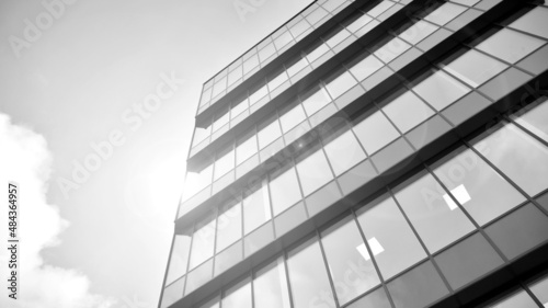 Modern glass and aluminum wall of office building outdoor with bright sun rays falling. Black and white.