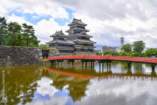 The red arch bridge connect across the deep moat to the Castle Matsumoto in summer Nagano  Japan.