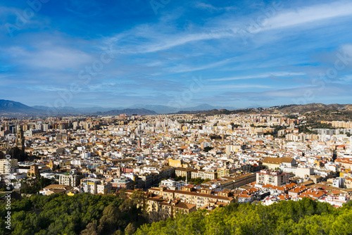 Aerial view of the Andalusian city of Malaga with a multitude of white houses and blue sky with light clouds.