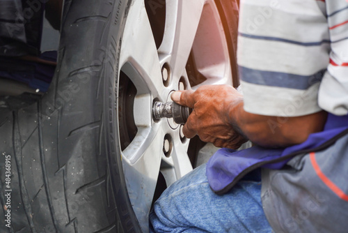 Asian mechanic uses air gun to remove wheels.concept of service or replacement. © Apicha