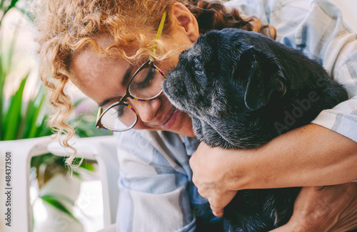 Love people and dog animal concept with happy adult caucasian woman and black old pug hugging and loving with tendernes together. Best friends forever concept