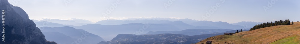 Panoramic view of the mountain ranges of the Dolomites covered in morning mist. Morning view from Seiser Alm plateau