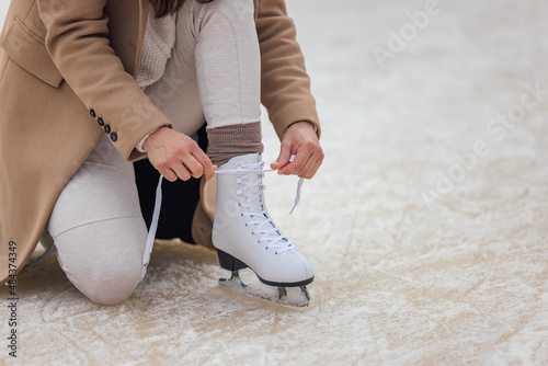 Close up of one white skate  tying her on the ice skate.