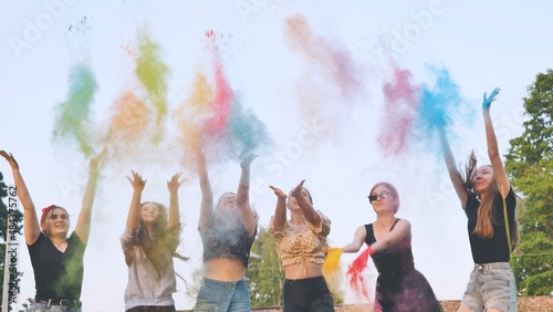 Cheerful female friends serve up holly colored powders on a summer day.