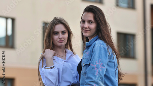 Two schoolgirls pose in front of their school.