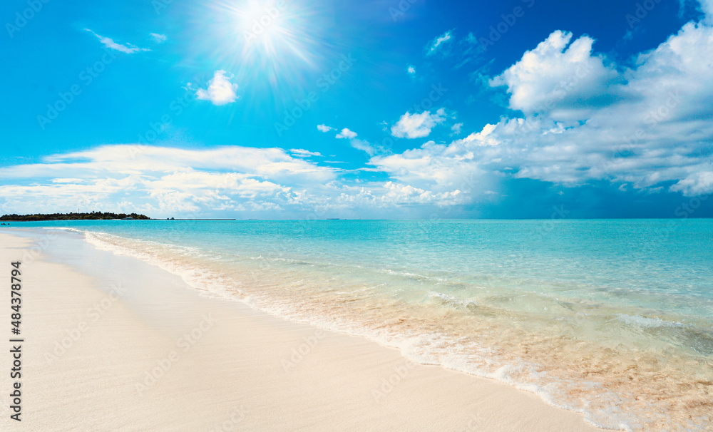 Beautiful background image of tropical beach. Bright summer sun over ocean. Blue sky with light clouds, turquoise ocean with surf and clear white sand. Harmony of clean environment.