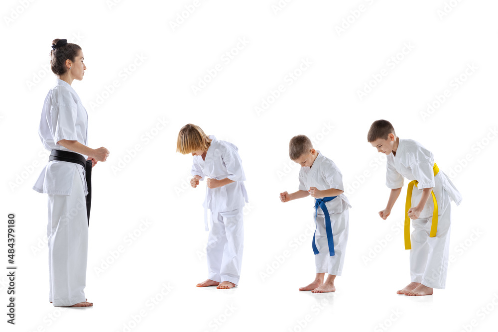 Group of kids, boys, taekwondo athletes wearing doboks training with master isolated on white background. Concept of sport, martial arts Group of kids, boys, taekwondo athletes wearing doboks training with master isolated on white background. Concept of sport, martial arts