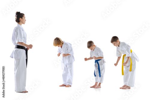 Group of kids, boys, taekwondo athletes wearing doboks training with master isolated on white background. Concept of sport, martial arts