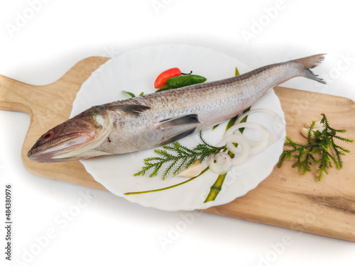 Greater lizardfish or wanieso saurida or Saurida tumbil decorated with herbs and vegetables on a wooden pad.Selective focus