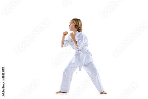 Portrait of sportive kid, male taekwondo, karate athletes in doboks jumping isolated on white background. Concept of sport, martial arts