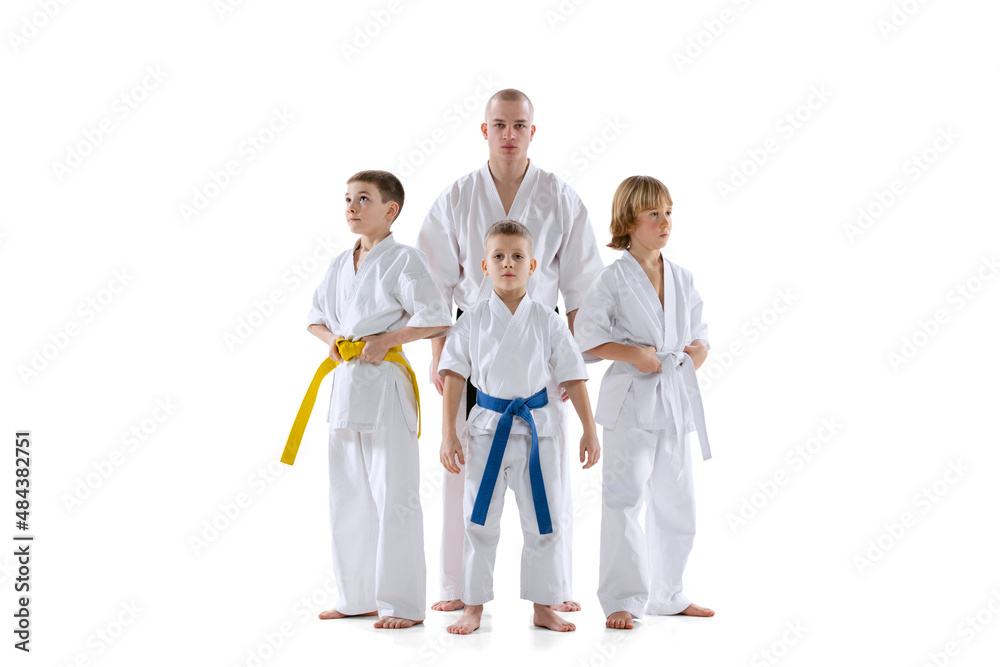 Portrait of group of kids, boys, taekwondo or karate athletes standing with master, coach isolated on white background. Concept of sport, martial arts Portrait of group of kids, boys, taekwondo or karate athletes standing with master, coach isolated on white background. Concept of sport, martial arts