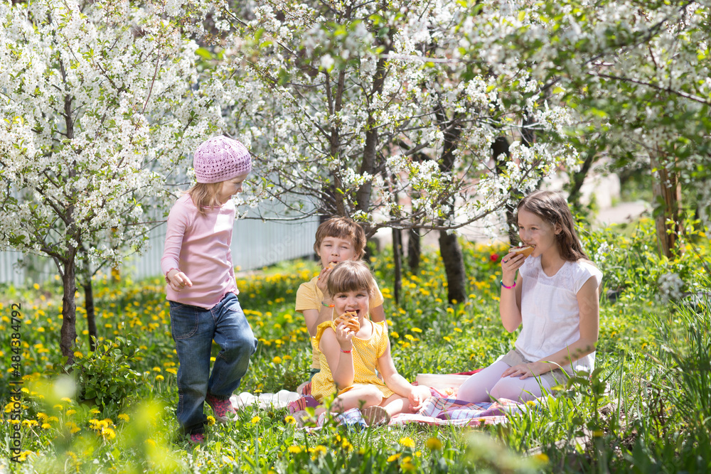 Fototapeta premium kids friends spend time together in nature. a group of children sit on the grass and having picnic in the spring garden
