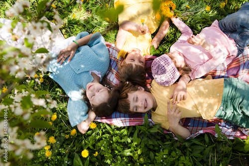 kids friends spend time together in nature. a group of children lies on the grass and rest in the summer garden