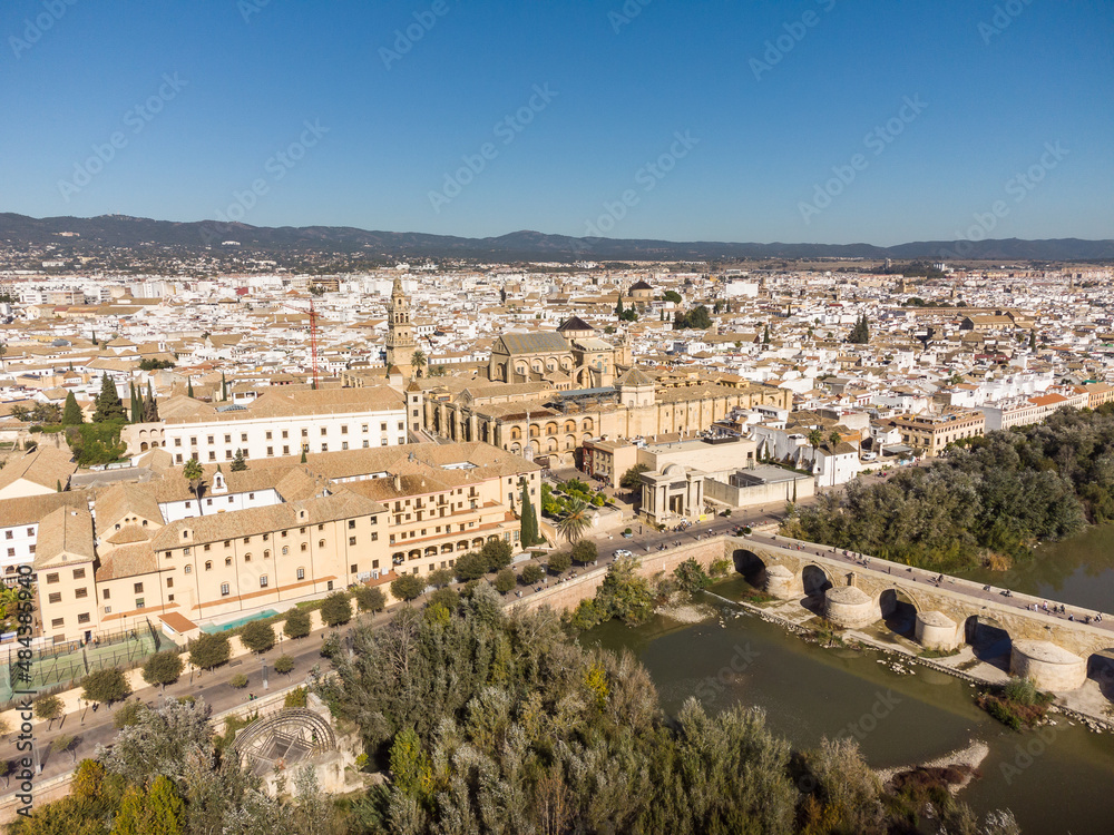 Dramatic aerial view of the famous Roman bridge above the Guadalquivir river along Cordoba old town in Andalusia in southern Spain on a sunny day