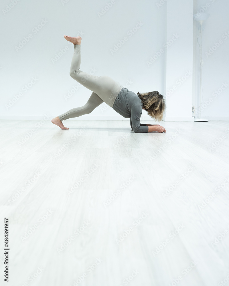 Naklejka premium Older woman doing yoga, in white room