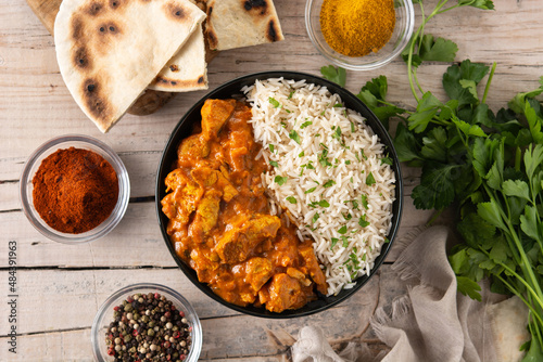 Indian butter chicken in black bowl on wooden table