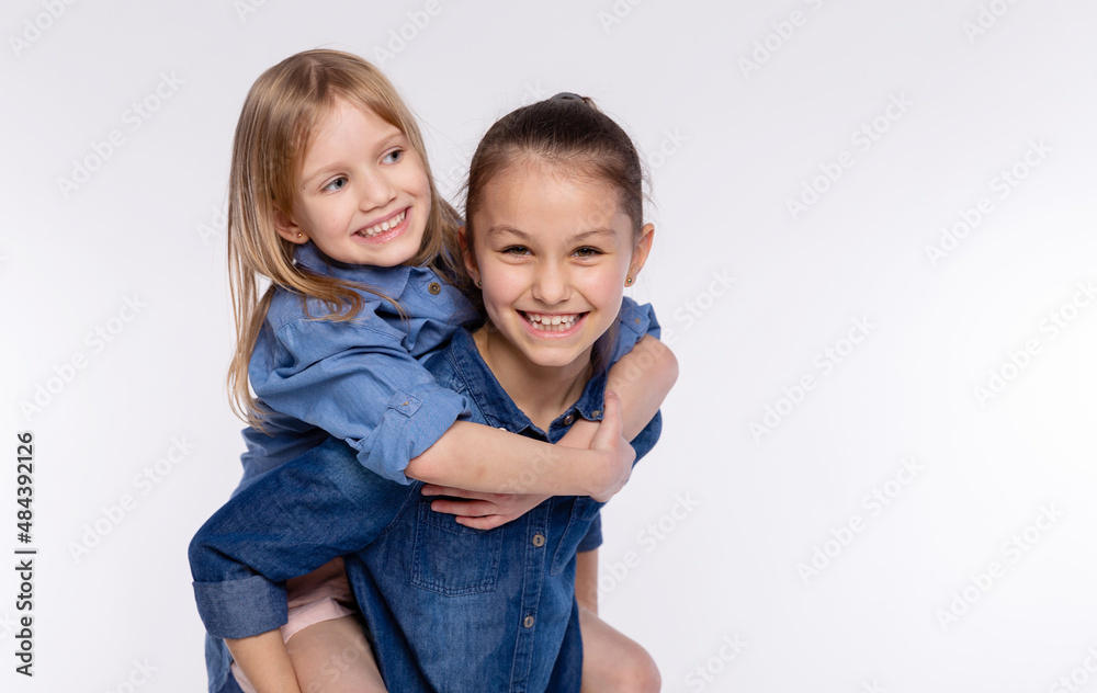 Two happy friends or sisters kid girls hugging. Together having fun and posing emotional on white background, happy smiling, friendship and relationship lifestyle people concept Two happy friends or sisters kid girls hugging. Together having fun and posing emotional on white background, happy smiling, friendship and relationship lifestyle people concept