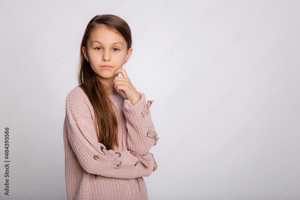 Obraz premium Portrait of a happy smiling child girl. Cute 8 years old girl face expression wearing pink sweater isolated over gray background