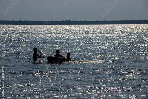 silhouettes of children swimming in the sun on the beach