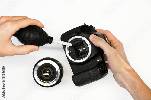 a man cleans the matrix of a reflex camera with an air pear close-up