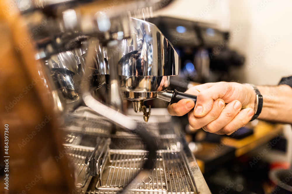 unrecognizable barista making espresso coffee in his coffee machine in a coffee shop
